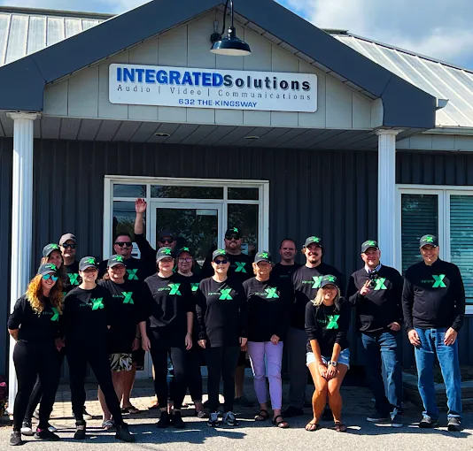 The Integrated Solutions team posing out front of their shop with smiles on.