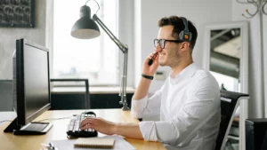 Man working on a desktop computer communicating through headphones