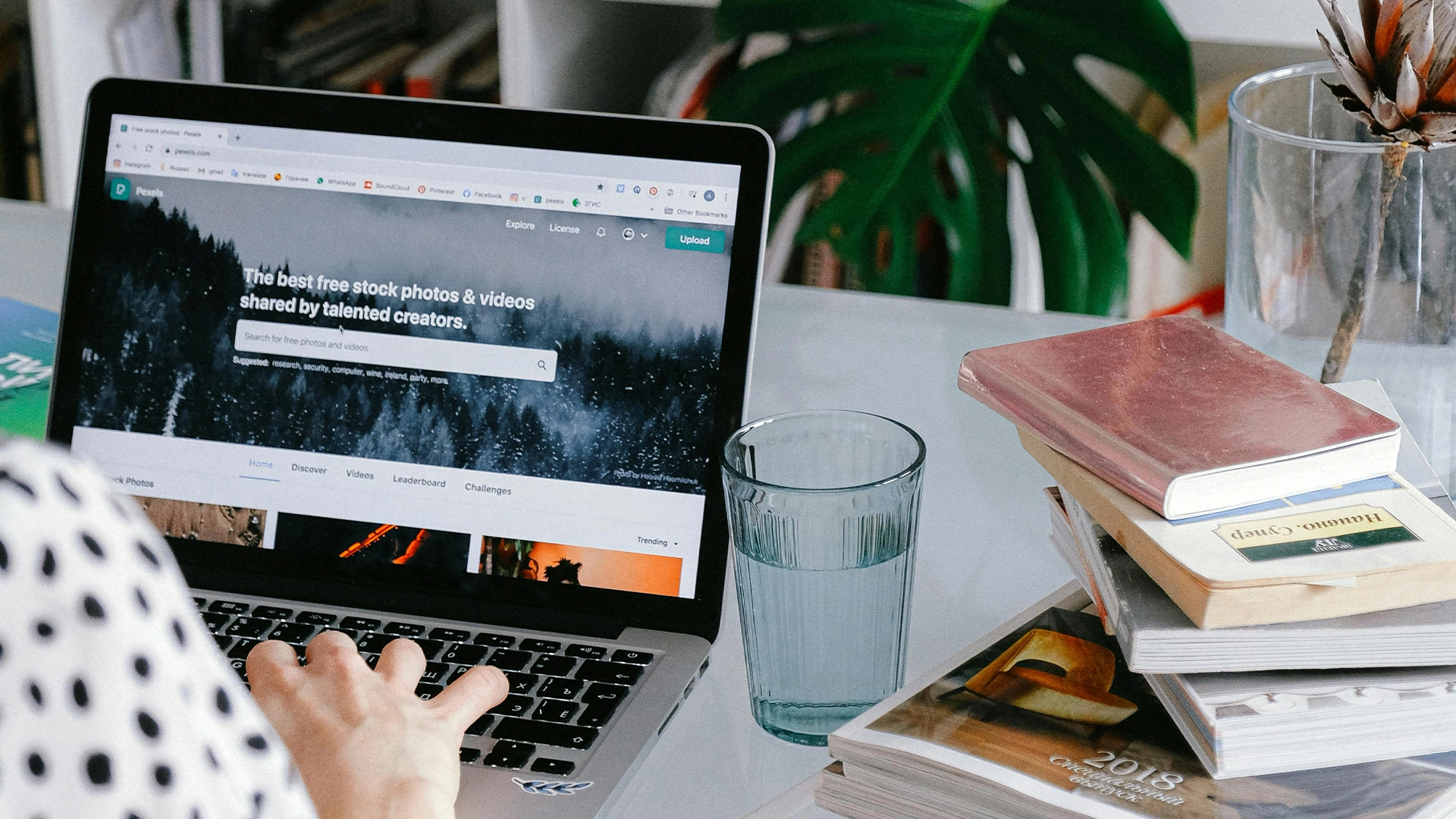 Woman on a Laptop next to a glass of water and a stack of books